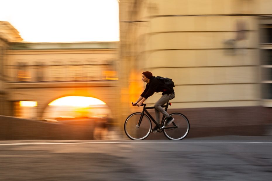 hipster cyclist rides through the city during sunset